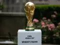 Złote trofeum FIFA World Cup na białym postumencie, symbol marzeń o zwycięstwie na **mistrzostwach świata 2030**.