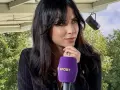 Maja Strzelczyk, dziennikarka sportowa, z mikrofonem Polsat Sport. W tle zielone drzewa i niebo.