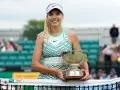 Katie Boulter z pucharem, uśmiechnięta na korcie tenisowym.