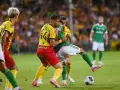 Piłkarze Legii Warszawa walczą o piłkę z zawodnikiem Korony Kielce. Emocjonujący mecz na boisku.