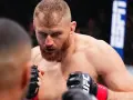Jan Błachowicz w skupieniu przed walką, zaciśnięte pięści w rękawicach UFC.