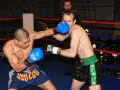 Dwóch zawodników wagi średniej UFC walczy w ringu. Jeden z nich wyprowadza cios, drugi blokuje.