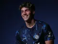 Uśmiechnięty Marc Guiu w ciemnogranatowej koszulce Chelsea z niebieskimi wzorami.