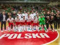 Drużyna Polski świętuje sukces na futsalowych mistrzostwach świata. Piłkarze w biało-czerwonych strojach z dumą pozują na tle napisu "POLSKA".