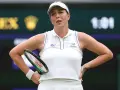 Anastasija Pawluczenkowa z rakietą, w białej koszulce Wimbledonu, zamyślona na korcie.