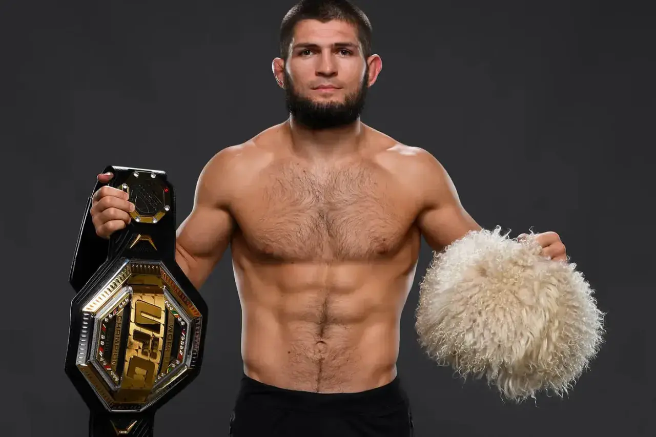 Khabib Nurmagomedov, jeden z najlepsi zawodnicy mma w historii, prezentuje pas UFC i tradycyjną czapkę.