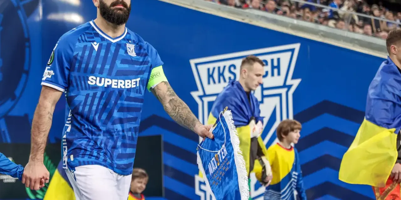 Piłkarz Lecha Poznań z flagą Szachtara na ręku, podczas meczu.