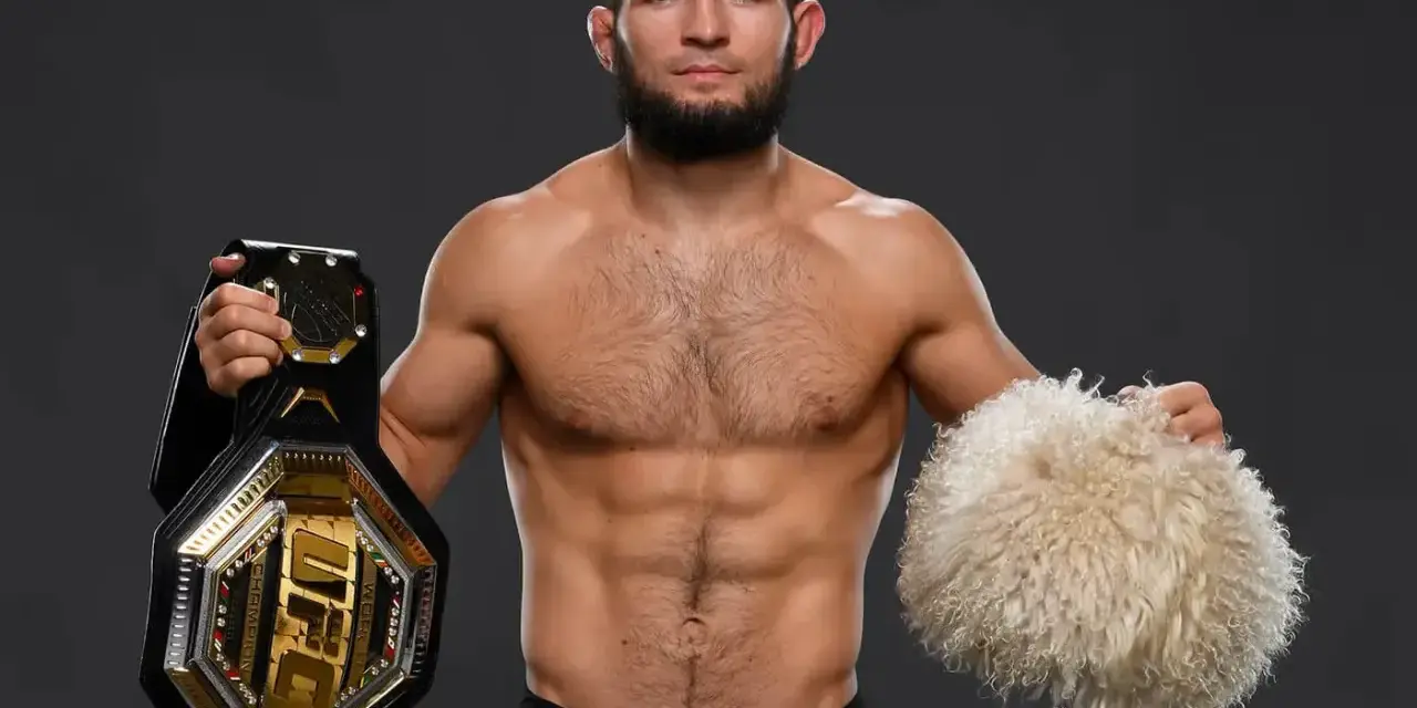 Khabib Nurmagomedov, jeden z najlepsi zawodnicy mma w historii, prezentuje pas UFC i tradycyjną czapkę.