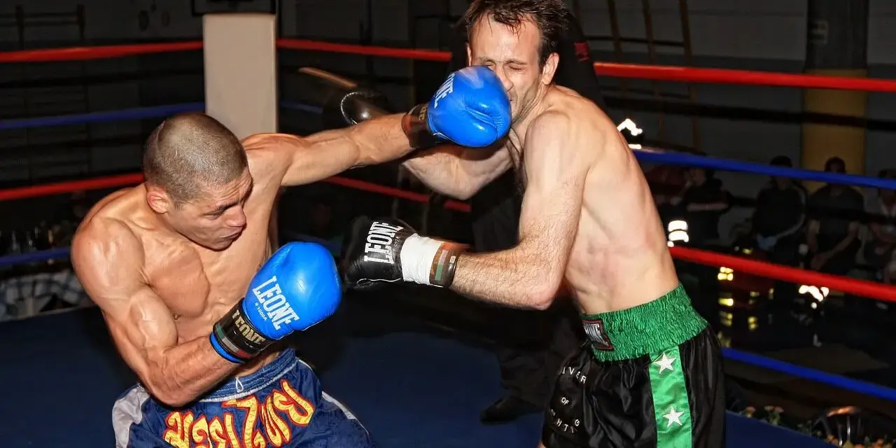 Dwóch zawodników wagi średniej UFC walczy w ringu. Jeden z nich wyprowadza cios, drugi blokuje.