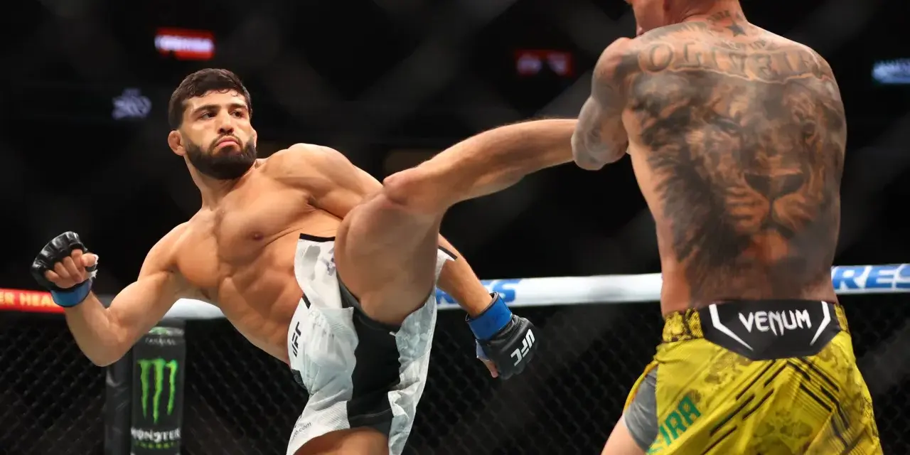 Waga półśrednia UFC: zawodnik wykonuje wysokie kopnięcie, jego przeciwnik z tatuażem lwa na plecach blokuje cios.