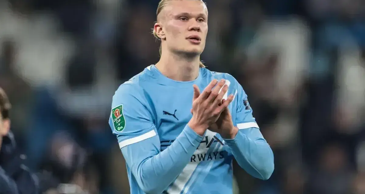 Erling Haaland w błękitnej koszulce Manchesteru City, z dłońmi złożonymi w geście uznania.