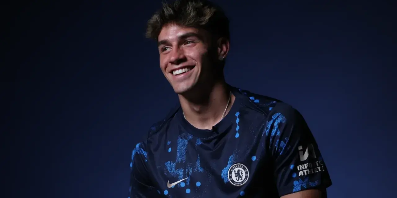Uśmiechnięty Marc Guiu w ciemnogranatowej koszulce Chelsea z niebieskimi wzorami.