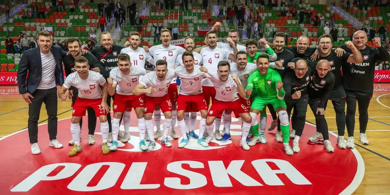 Drużyna Polski świętuje sukces na futsalowych mistrzostwach świata. Piłkarze w biało-czerwonych strojach z dumą pozują na tle napisu "POLSKA".