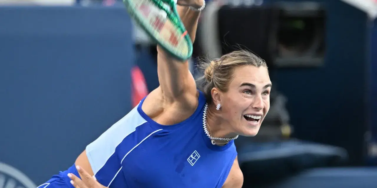 Aryna Sabalenka w akcji, z rakietą w górze, gotowa do serwisu. Widać jej skupienie i determinację, kiedy gra Sabalenka.