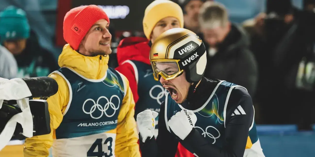 Philipp Raimund w złoto-czarnym kasku i goglach krzyczy z radości, obok kolega w czerwonej czapce i żółtej kurtce.