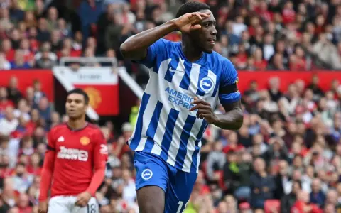 Piłkarz Brighton w niebiesko-białej koszulce świętuje bramkę przeciwko Man Utd. Casemiro z Manchesteru United w tle.