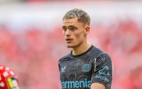Młody piłkarz Florian Wirtz w koszulce Bayer Leverkusen, skupiony na boisku.