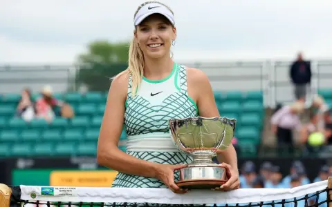 Katie Boulter z pucharem, uśmiechnięta na korcie tenisowym.