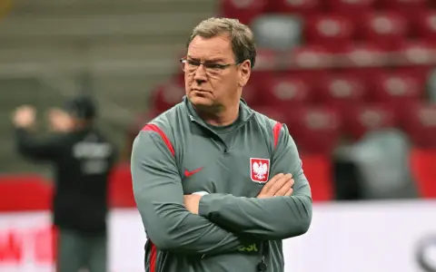 Trener reprezentacji Polski w piłce nożnej, z założonymi rękami, w okularach, zastanawia się, ile zarabia.