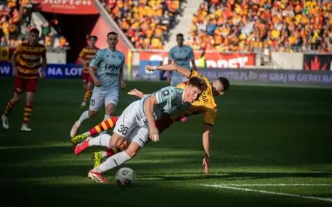 Zacięta walka na boisku podczas meczu Jagiellonia Białystok – Piast. Piłkarze walczą o piłkę, jeden z nich upada.