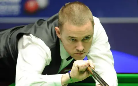 Gracz snookera w skupieniu celuje kijem do bili. Czy to on zostanie mistrzem świata w snookerze 2025?