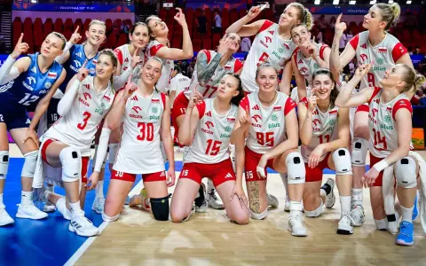 Siatkarki reprezentacji Polski w siatkówce, uśmiechnięte, pozują do zdjęcia, wskazując palcami w górę.
