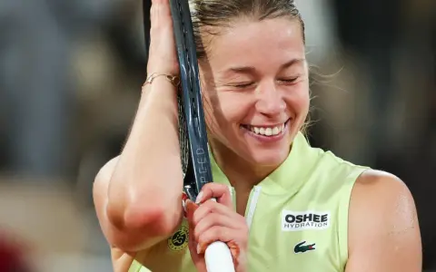 Szczęśliwa Iga Świątek, zwyciężczyni Roland Garros, z rakietą opartą o głowę, w geście triumfu.