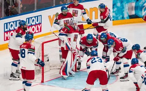 Czescy hokeiści w akcji podczas mistrzostw świata w hokeju 2024. Drużyna w białych strojach z czerwonymi i niebieskimi elementami walczy o zwycięstwo.