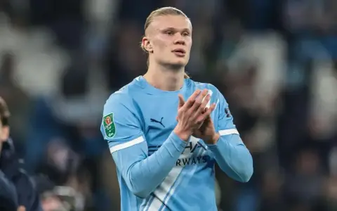 Erling Haaland w błękitnej koszulce Manchesteru City, z dłońmi złożonymi w geście uznania.