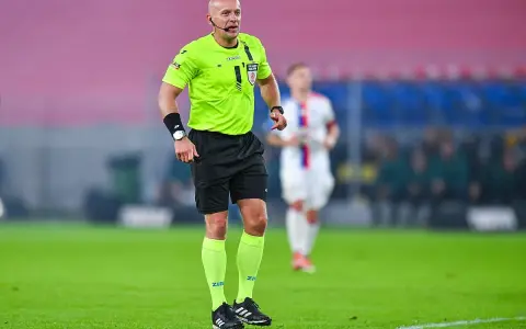Sędzia piłkarski w jaskrawej koszulce, jeden z wielu polskich sędziów piłkarskich, czuwa nad przebiegiem meczu na zielonej murawie.