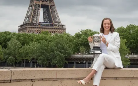 Iga Świątek z pucharem Roland Garros w Paryżu, z Wieżą Eiffla w tle.
