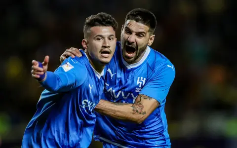 Dwóch piłkarzy Al Hilal w niebieskich koszulkach świętuje bramkę. Jeden z nich krzyczy z radości, drugi wskazuje palcem.