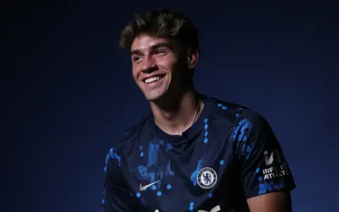 Uśmiechnięty Marc Guiu w ciemnogranatowej koszulce Chelsea z niebieskimi wzorami.