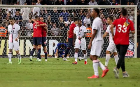 Piłkarze PSG i Lille świętują po meczu. Jeden z zawodników Lille klęczy na boisku.