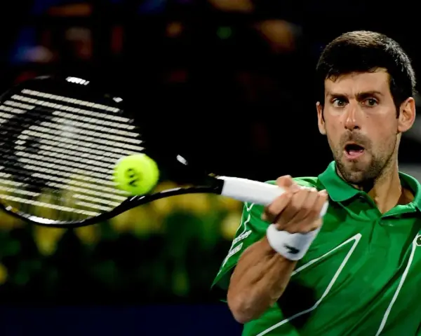 Novak Djoković, jeden z zwycięzców US Open, uderza piłkę rakietą.