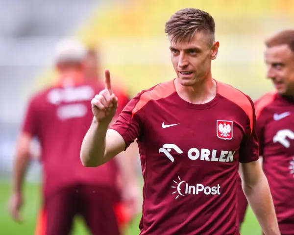 Krzysztof Piątek, w koszulce z orłem, pokazuje palcem do góry. Jego nowy krzysztof piątek transfer budzi nadzieję.