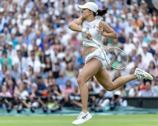 Tenisistka w akcji na korcie podczas WTA Berlin. Dynamiczny ruch, rakieta w dłoni, tłum kibiców na trybunach.