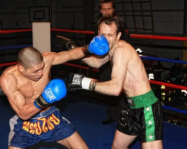 Dwóch zawodników wagi średniej UFC walczy w ringu. Jeden z nich wyprowadza cios, drugi blokuje.