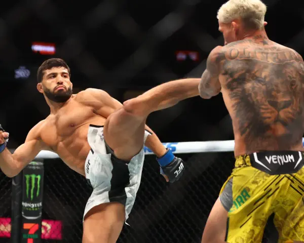 Waga półśrednia UFC: zawodnik wykonuje wysokie kopnięcie, jego przeciwnik z tatuażem lwa na plecach blokuje cios.