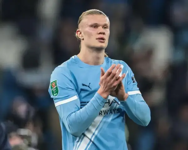 Erling Haaland w błękitnej koszulce Manchesteru City, z dłońmi złożonymi w geście uznania.
