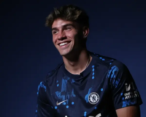 Uśmiechnięty Marc Guiu w ciemnogranatowej koszulce Chelsea z niebieskimi wzorami.