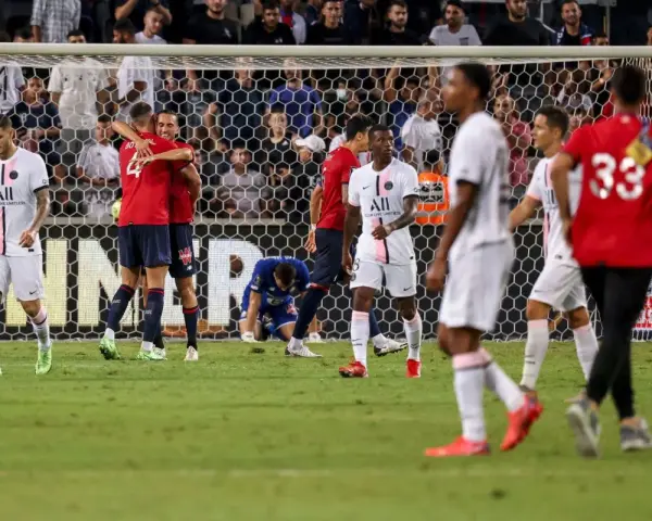 Piłkarze PSG i Lille świętują po meczu. Jeden z zawodników Lille klęczy na boisku.
