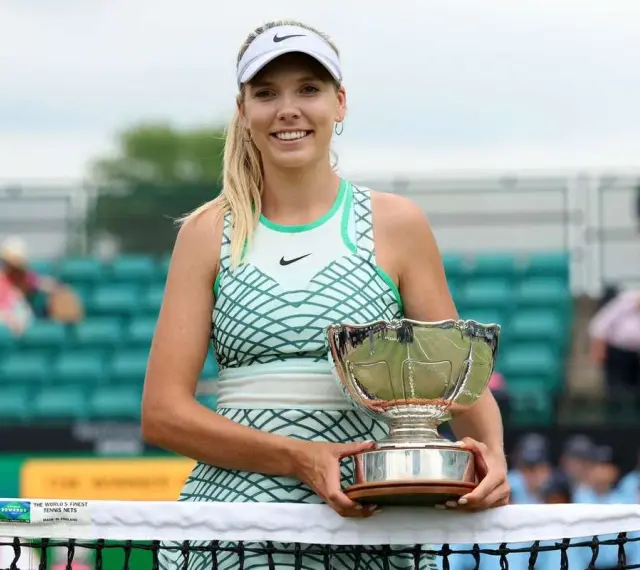 Katie Boulter z pucharem, uśmiechnięta na korcie tenisowym.