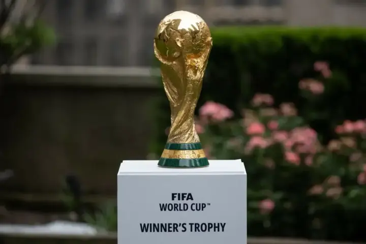 Złote trofeum FIFA World Cup na białym postumencie, symbol marzeń o zwycięstwie na **mistrzostwach świata 2030**.