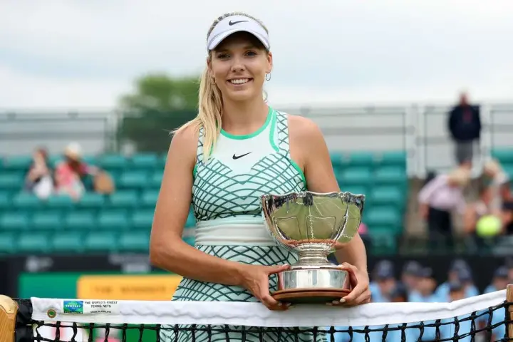 Katie Boulter z pucharem, uśmiechnięta na korcie tenisowym.