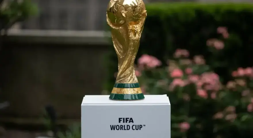 Złote trofeum FIFA World Cup na białym postumencie, symbol marzeń o zwycięstwie na **mistrzostwach świata 2030**.