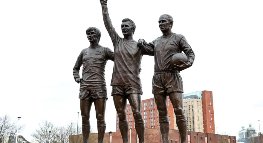 Pomnik trzech legend Manchesteru United: Charlton, Law i Best. Ich postacie upamiętniają złote lata klubu.