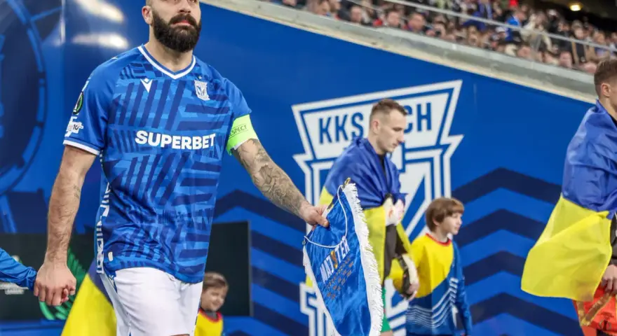 Piłkarz Lecha Poznań z flagą Szachtara na ręku, podczas meczu.