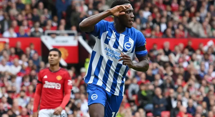 Piłkarz Brighton w niebiesko-białej koszulce świętuje bramkę przeciwko Man Utd. Casemiro z Manchesteru United w tle.