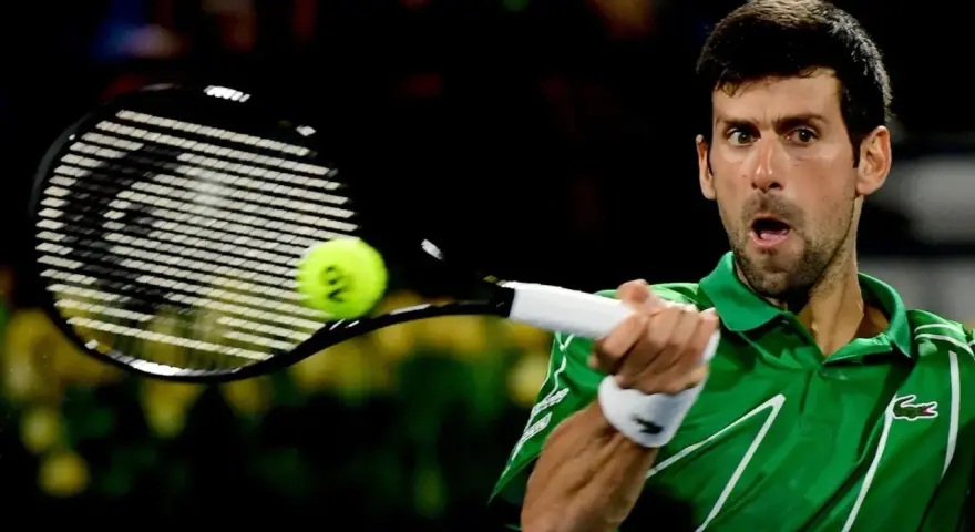 Novak Djoković, jeden z zwycięzców US Open, uderza piłkę rakietą.